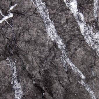 Grigio Carnico marble texture with dark gray base, black veining, and white streaks displaying a polished, web-like pattern.